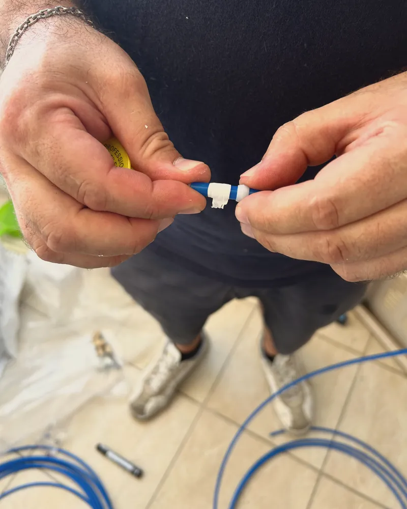 Mani di un tecnico che innestano un tubo blu in un raccordo