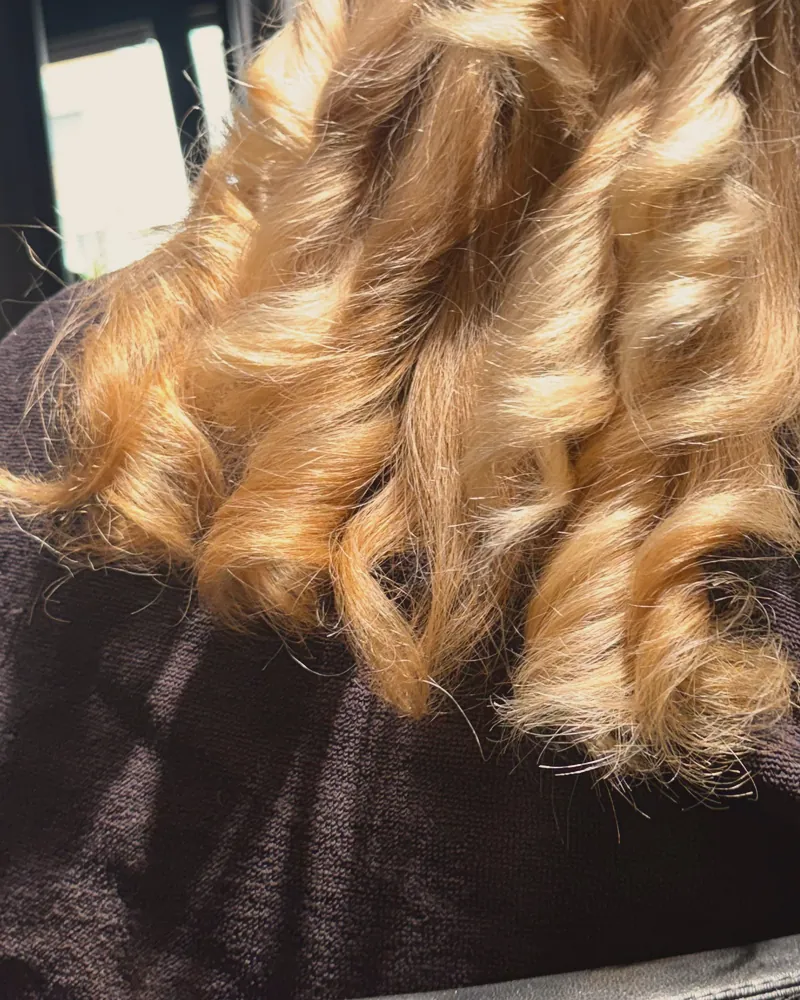 Onde bionde viste da dietro su un mantello nero, in salone